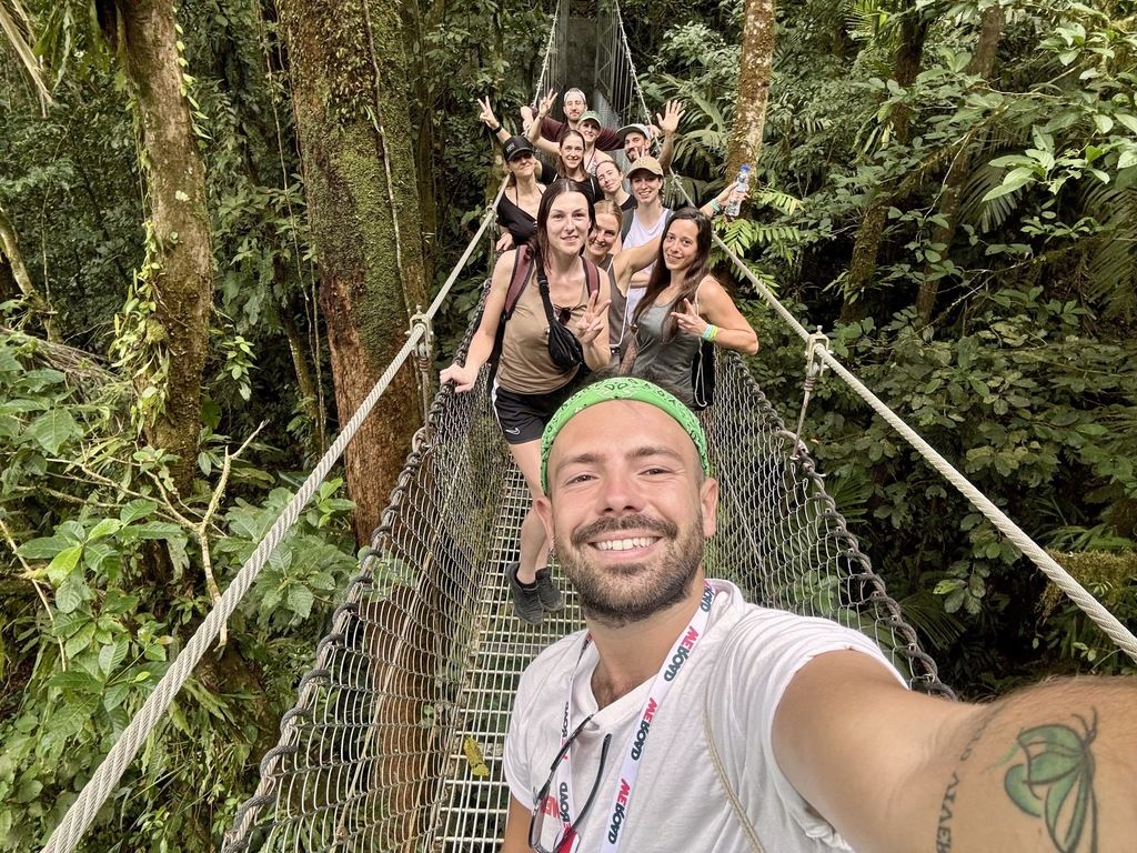 Selfie of a cheerful WeRoad group crossing a suspension bridge on a jungle trek in Costa Rica.