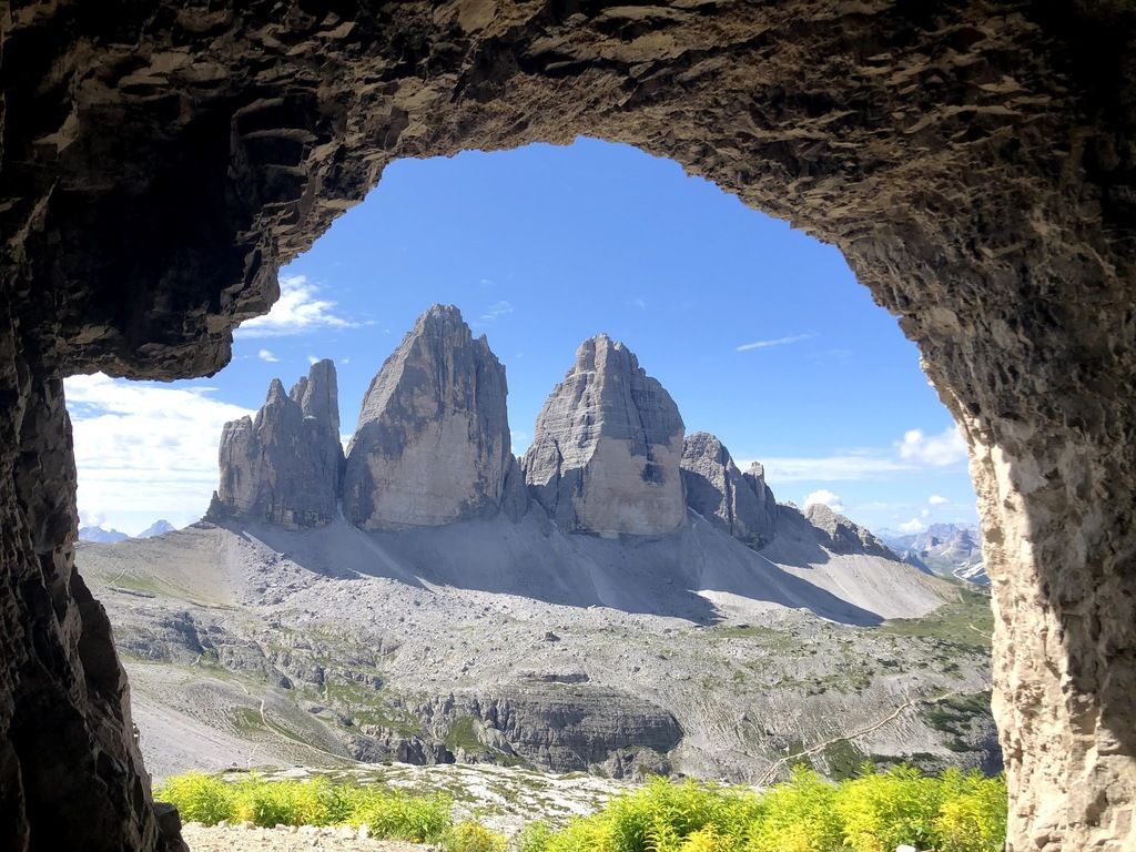 View of the Three Peaks of Lavaredo framed by a cave in the Dolomites