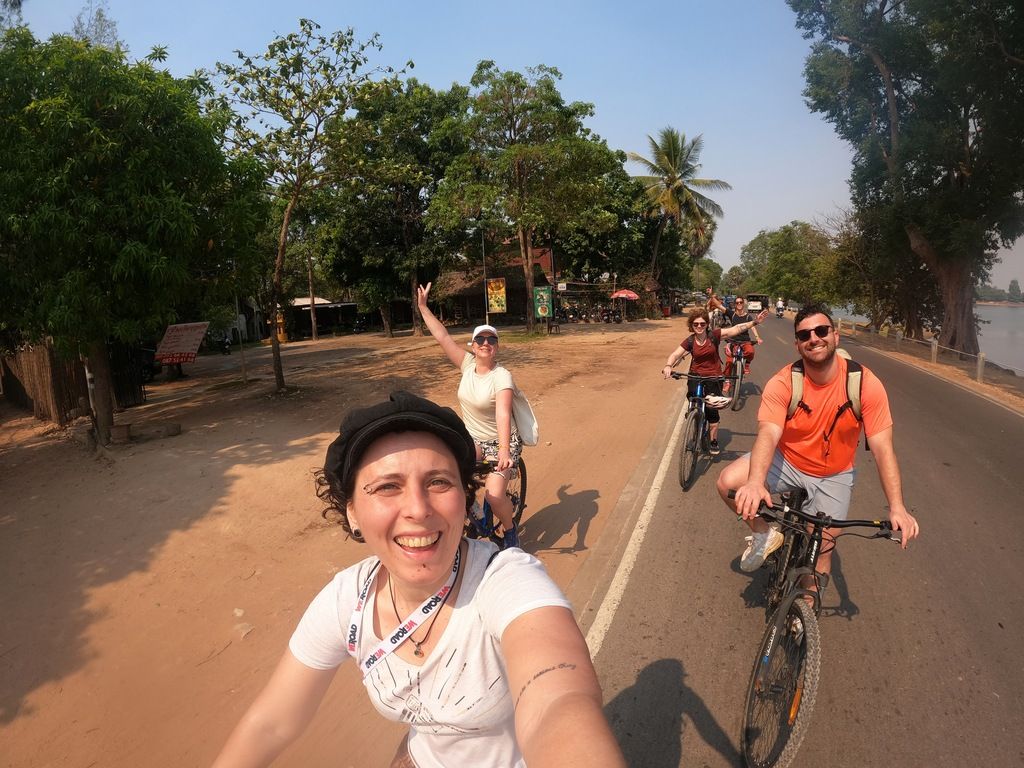 Group of happy cyclists riding along a rural road during a sunny day in Southeast Asia