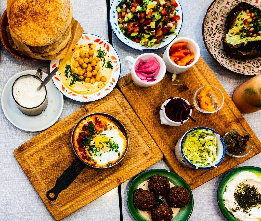 Traditional Middle Eastern mezze spread with hummus, shakshuka, falafel, pickled vegetables, fresh salad, and pita bread
