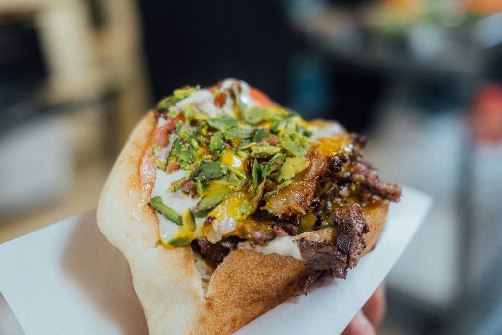 Shawarma sandwich topped with tahini, pistachios and grilled meat