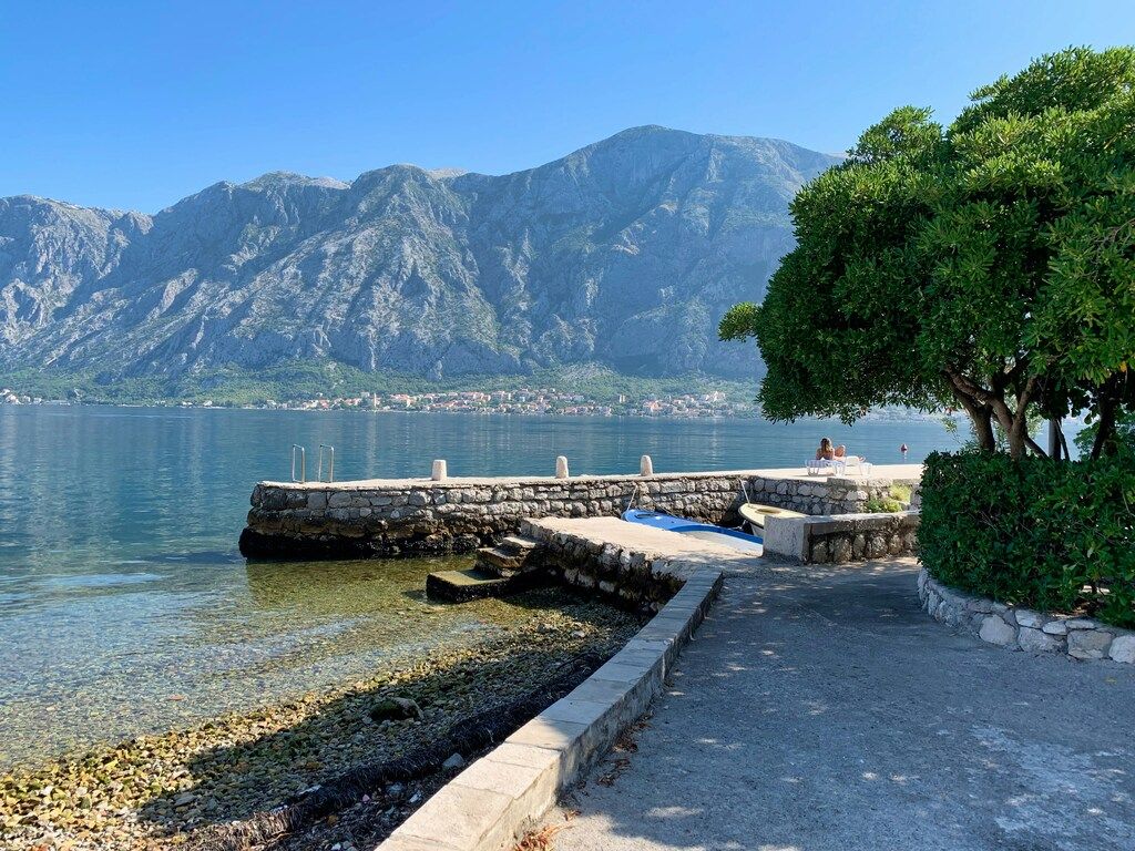 Tranquil view of the Bay of Kotor with stone pier and mountains in the background