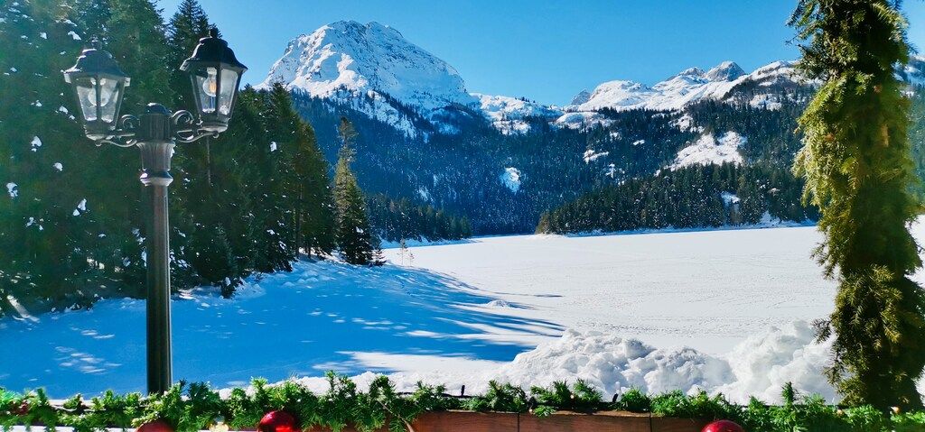 Snow-covered Black Lake and Durmitor mountains in winter with pine trees and festive decorations