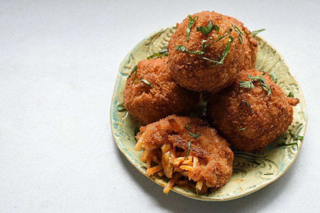 Crispy spaghetti-filled arancini served on a ceramic plate