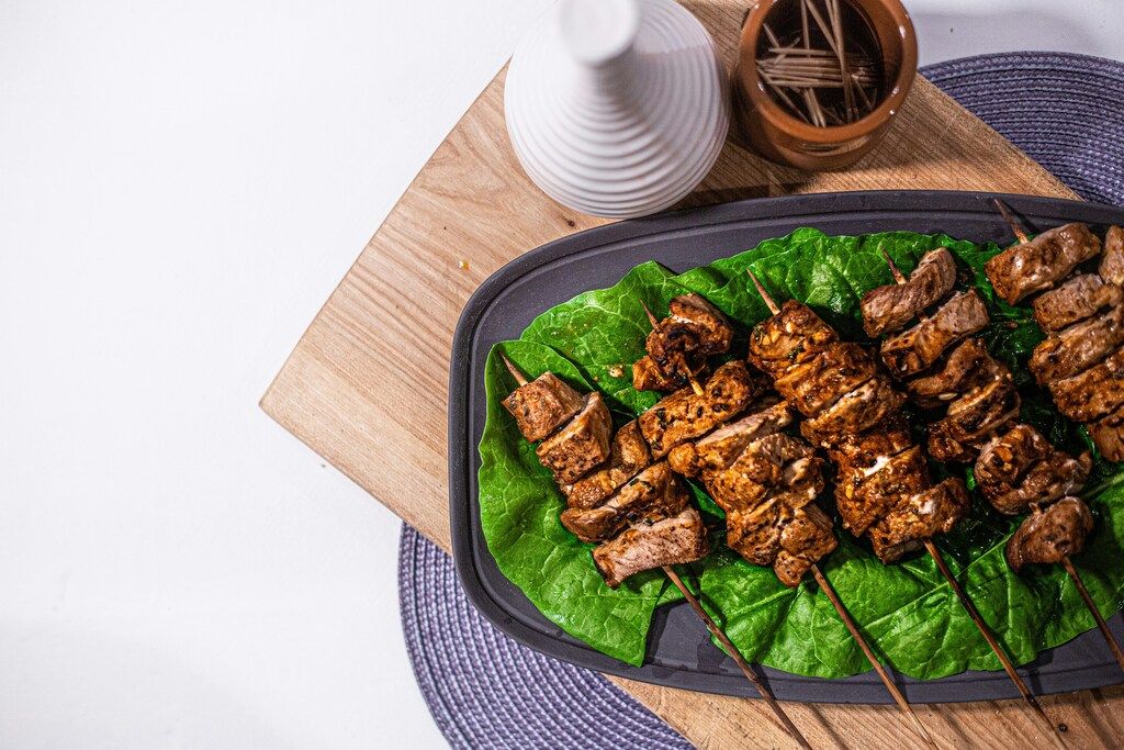 Grilled meat skewers served on lettuce leaves on a wooden board