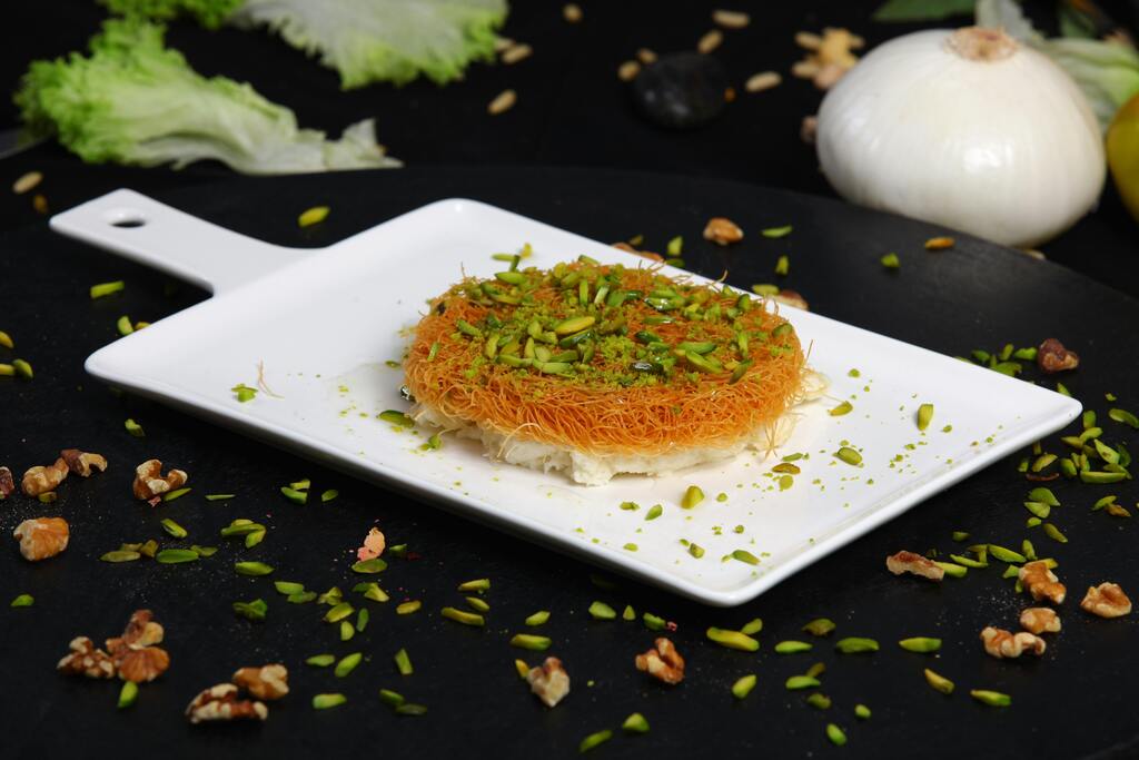 Konafa with pistachios on a white plate