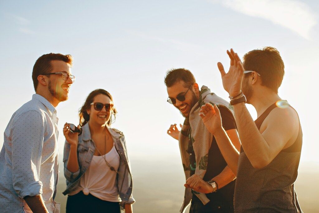 Group of friends laughing outdoors in sunlight.