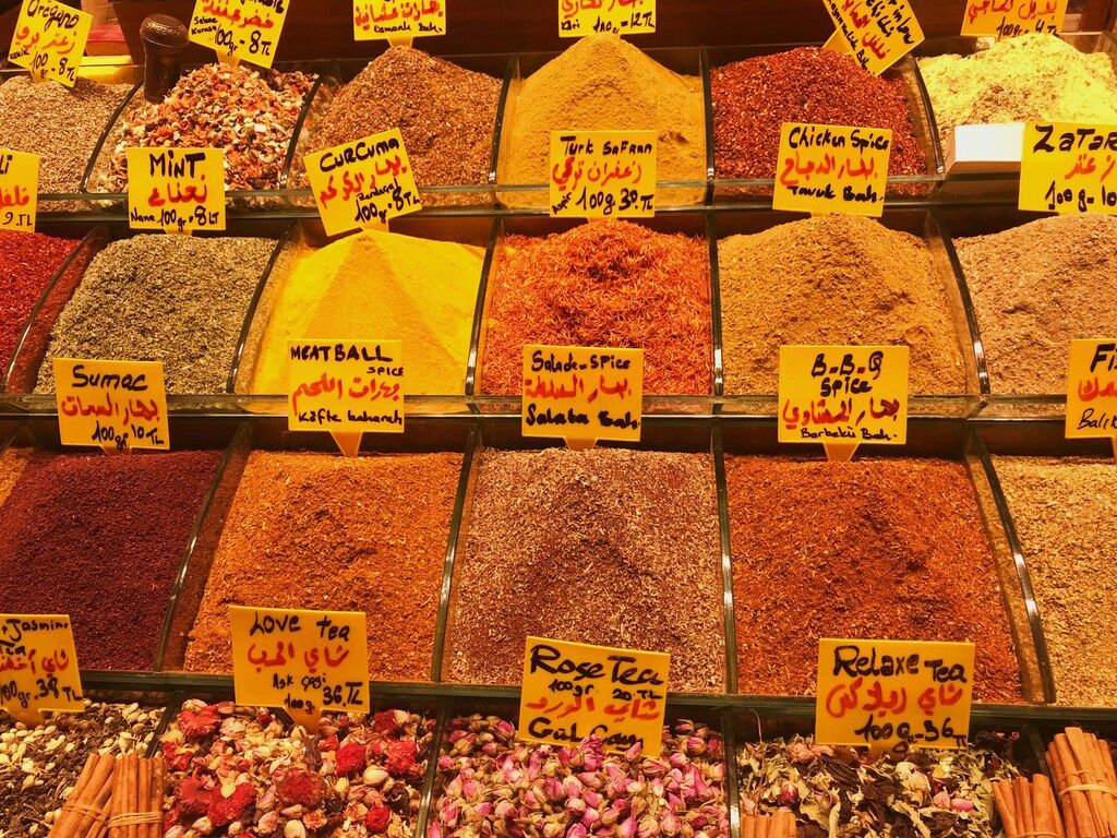A market stall displaying various colorful spices and teas in bins with labels.