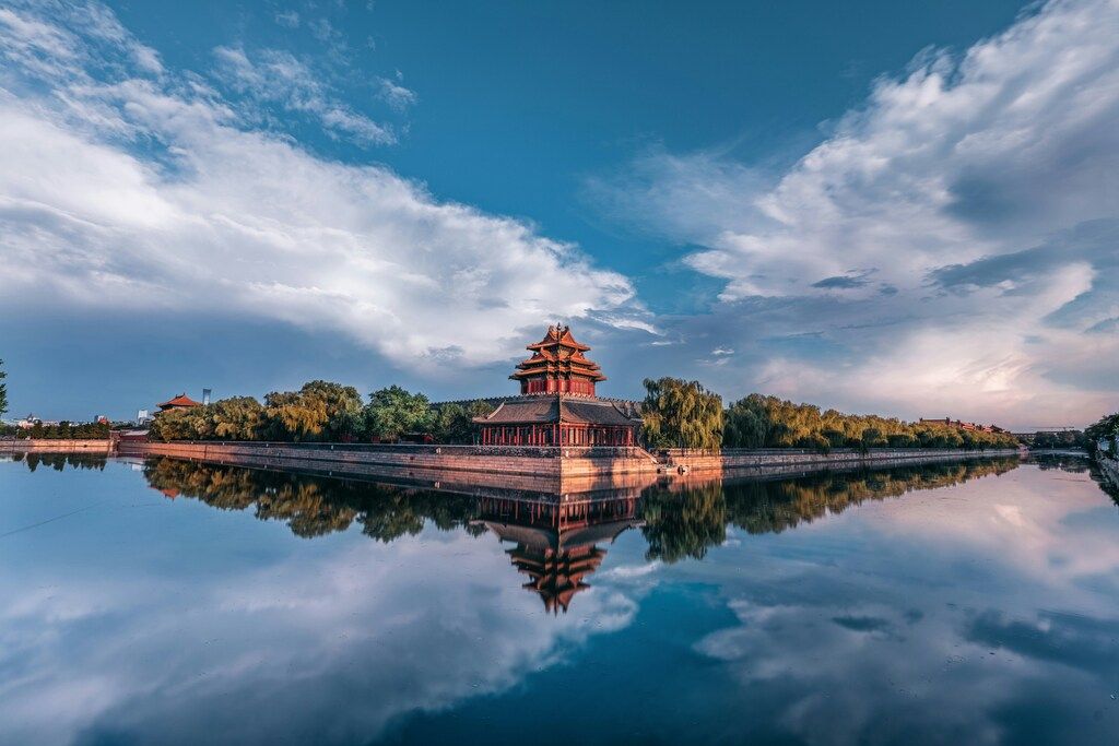 Scenic view of a watchtower of the Forbidden City reflected in the moat under a dramatic sky in Beijing, China.
