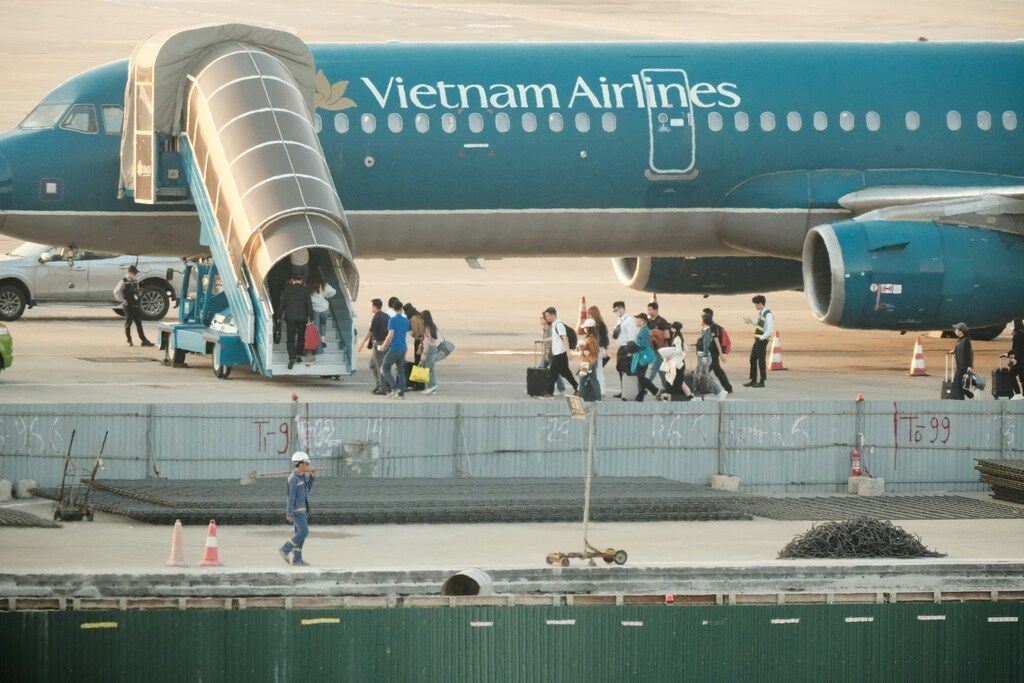 Passengers boarding a Vietnam Airlines plane on the tarmac at an airport.