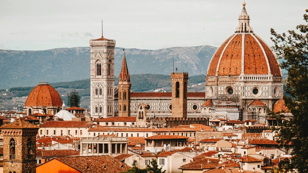 Panoramic view of Florence with the iconic red dome of the Duomo and Giotto's Bell Tower standing above the city rooftops.