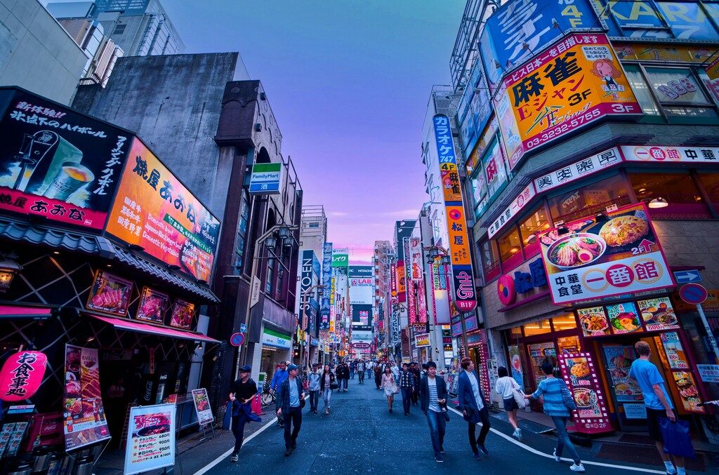 Colorful street in Tokyo filled with bright signs, restaurants, and people strolling in the evening.