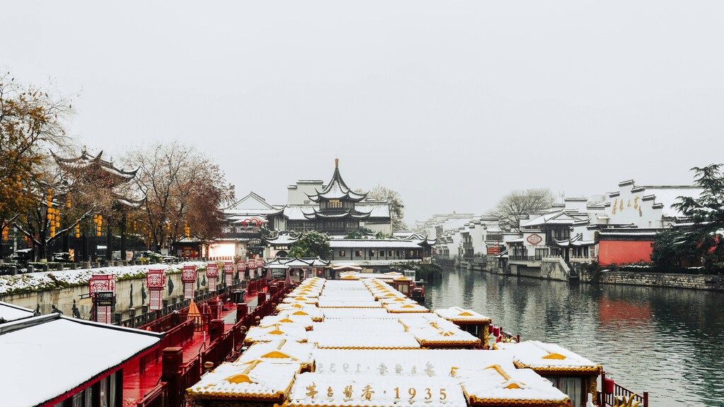 Traditional buildings and canal boats covered in snow in the historic district of Nanjing, China.