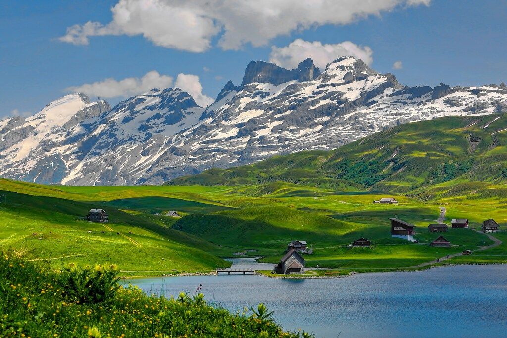 Scenic view of alpine houses and snowy peaks by a lake in the Swiss Alps, Switzerland.
