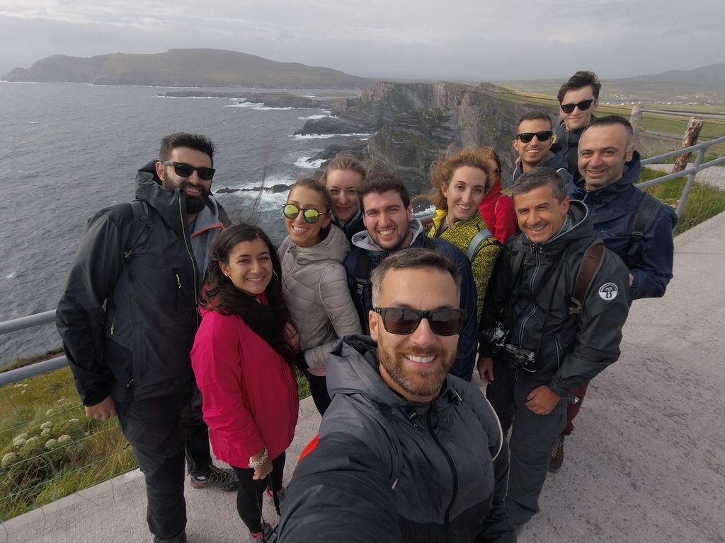 WeRoad group selfie with dramatic cliffs and the ocean on the Wild Atlantic Way, Ireland.