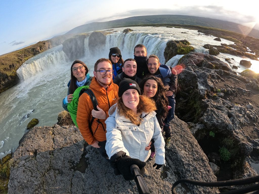 Group selfie in front of the Godafoss waterfall in Iceland during a WeRoad group trip.