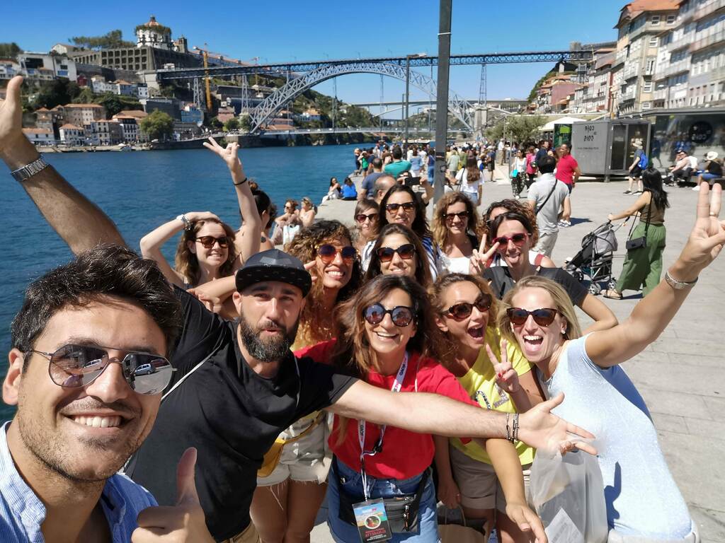 Cheerful WeRoad group selfie along the Douro River promenade in Porto, Portugal.