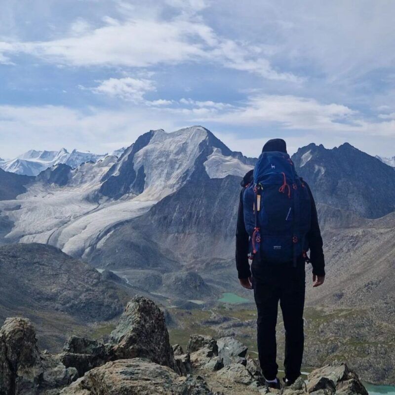 Hiker with his back turned, contemplating the mountainous landscape of Kyrgyzstan.