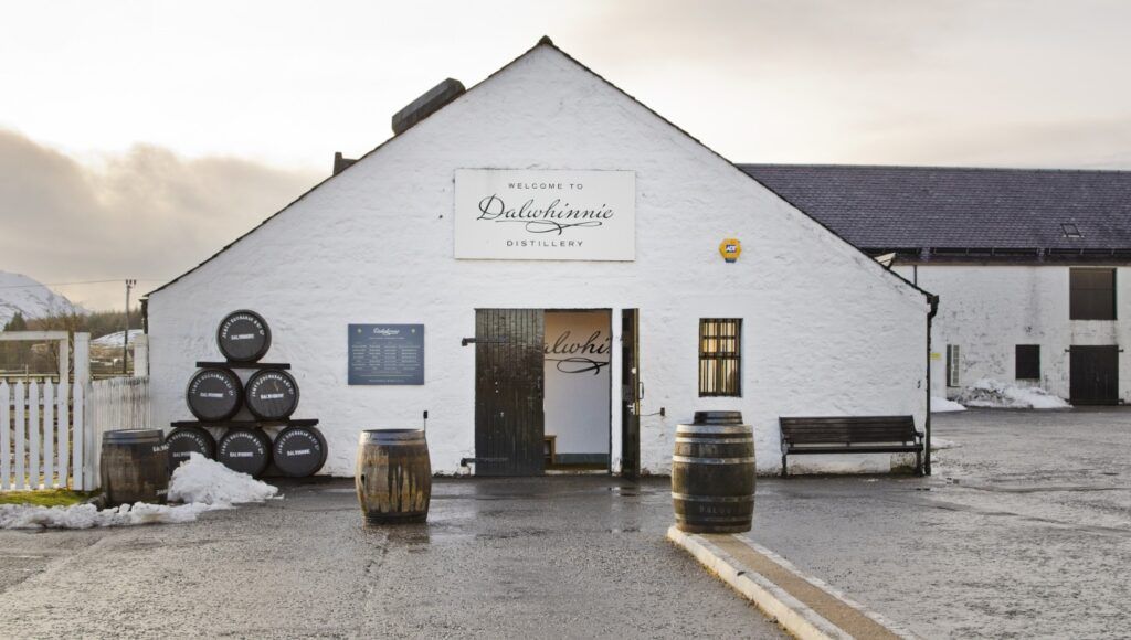 The exterior of a Scottish distillery with stacks of whisky barrels.