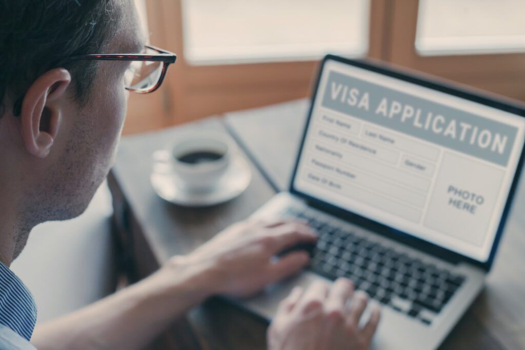 Man filling out a visa application form online on a laptop.