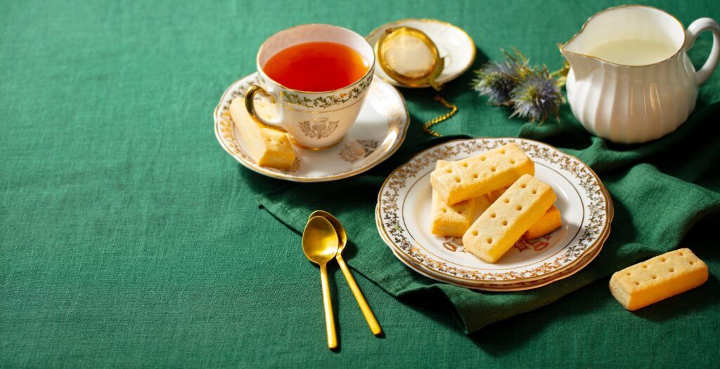 A cup of tea next to a plate of Scottish shortbread cookies.

