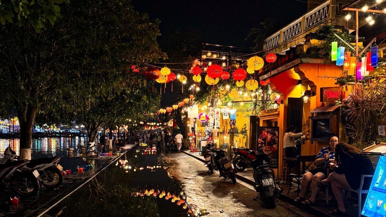 A street in Hoi An, Vietnam, is lit up at night with numerous colorful lanterns strung between buildings.