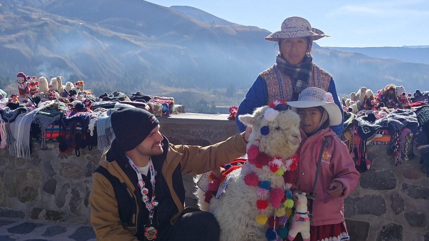 Man posing with local women and decorated alpaca in the Peruvian Andes.