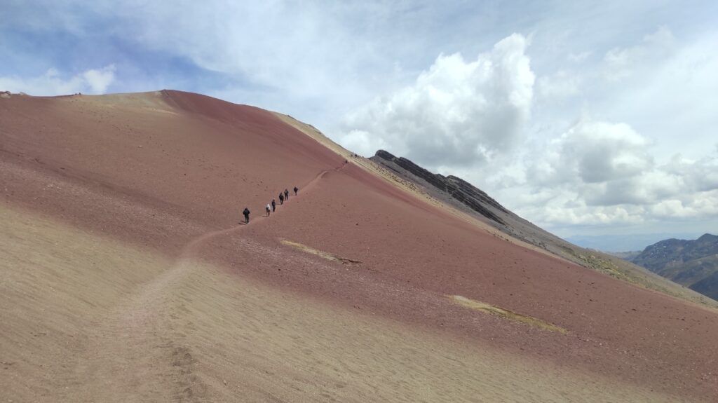 Group of hikers climbing the red slopes of Vinicunca mountain, Peru.