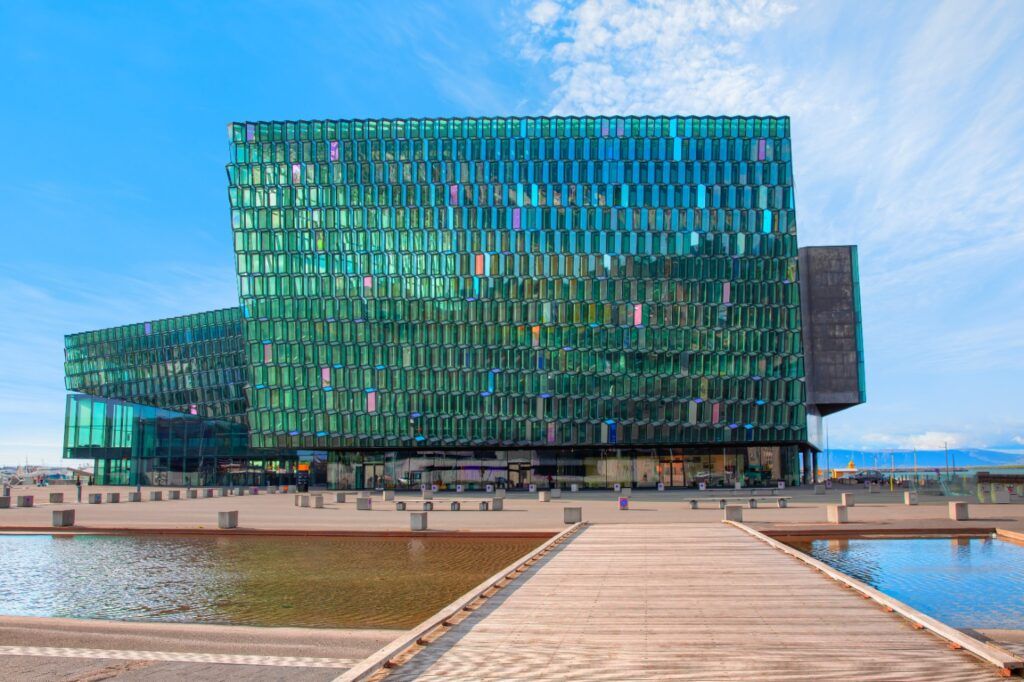 Hexagonal green glass façade of the Harpa Concert Hall in Reykjavík, with ponds in the foreground.