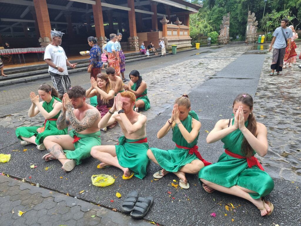 WeRoad Travelers in sarongs praying at a temple in Bali.