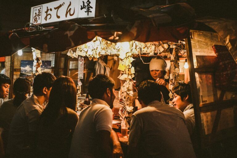 People gathered at a lively Japanese street food stall at night