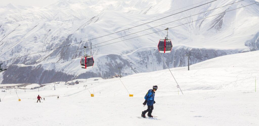 Gondola lift ascending over the vast, empty Caucasus slopes of the Gudauri ski resort in Georgia.