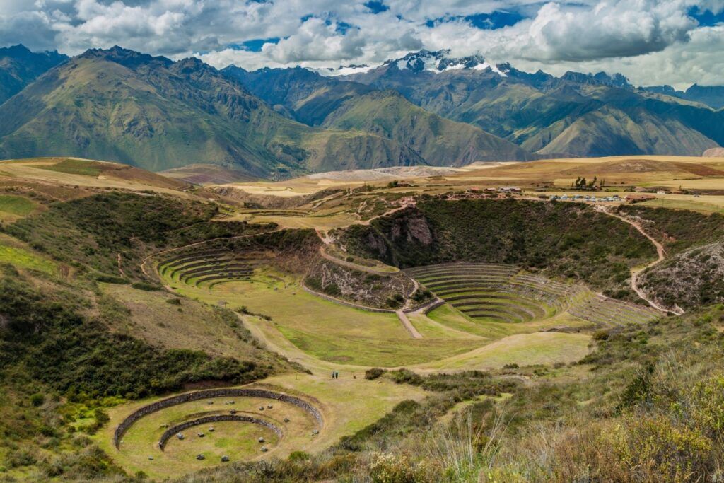 Panoramic view of the circular Inca terraces of Moray with Andes mountains in the background.