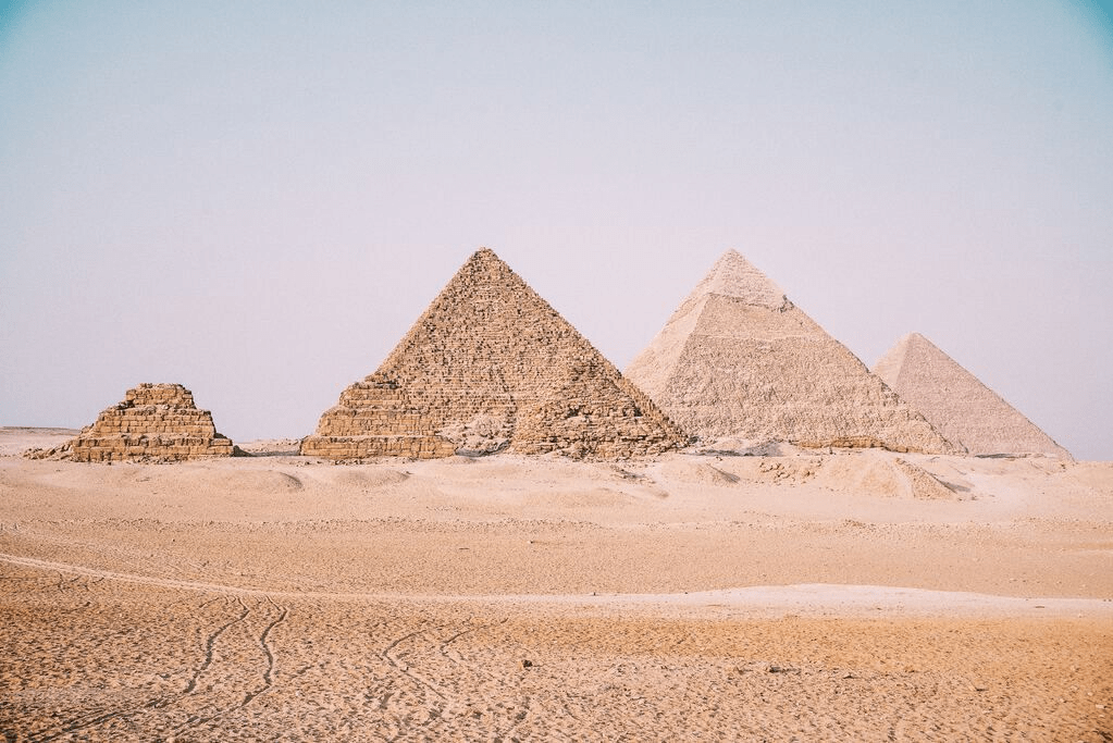 The Pyramids of Giza standing in the desert landscape under a clear sky.