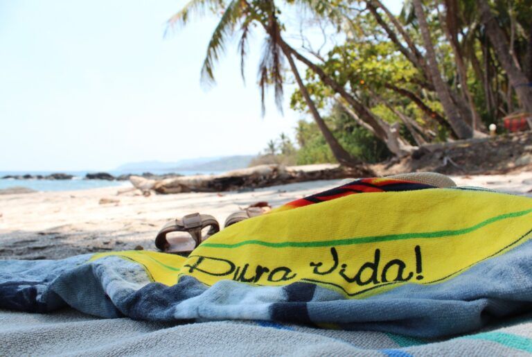 Yellow towel with "Pura Vida!" on a sandy beach in Costa Rica.