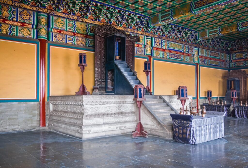 Ornate interior of a Temple of Heaven building with a stepped stone platform and carved wooden shrine