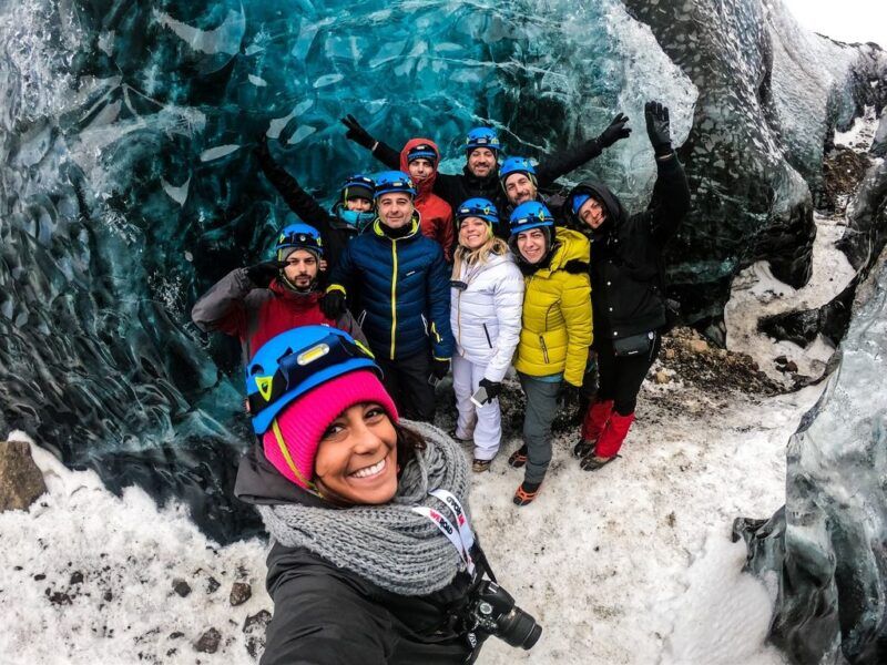 A WeRoad travelers take a selfie inside a bright blue ice cave in Iceland.