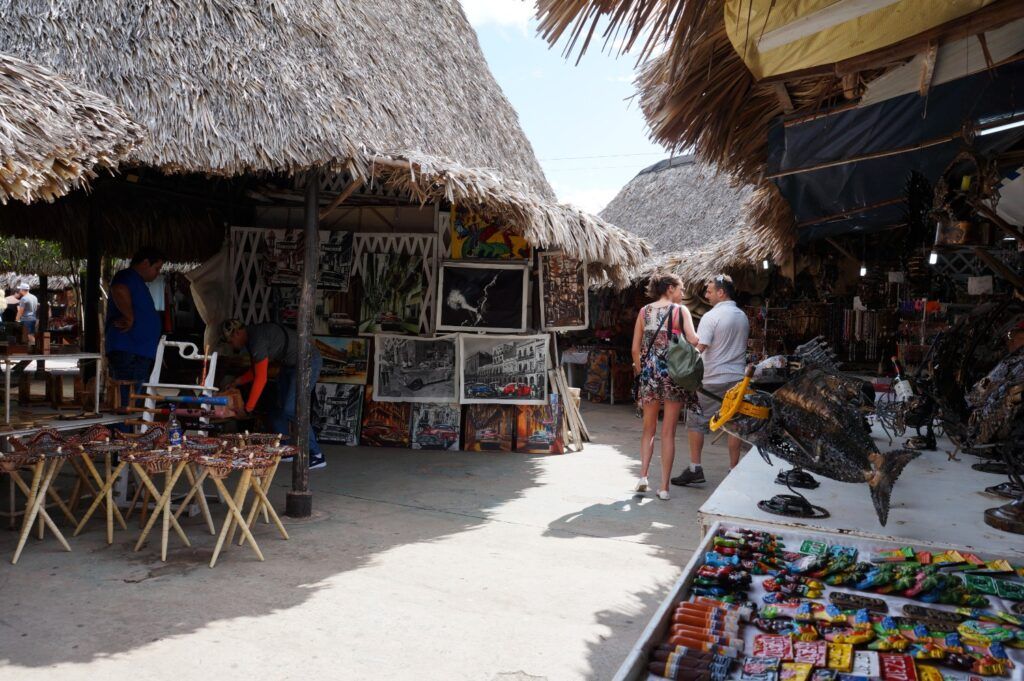 Tourists browsing local artwork and souvenirs at an outdoor craft market in Cuba.