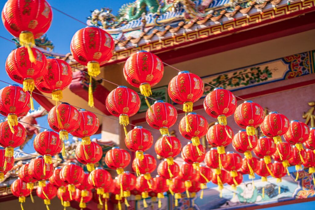 Numerous traditional red lanterns hanging in front of a decorated temple, symbolizing the Chinese New Year festivities.