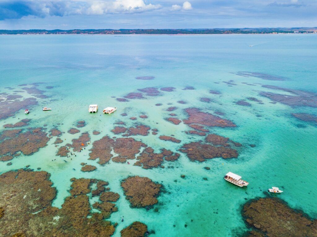 Natural pools of Maragogi showing turquoise waters and coral reefs with boats.