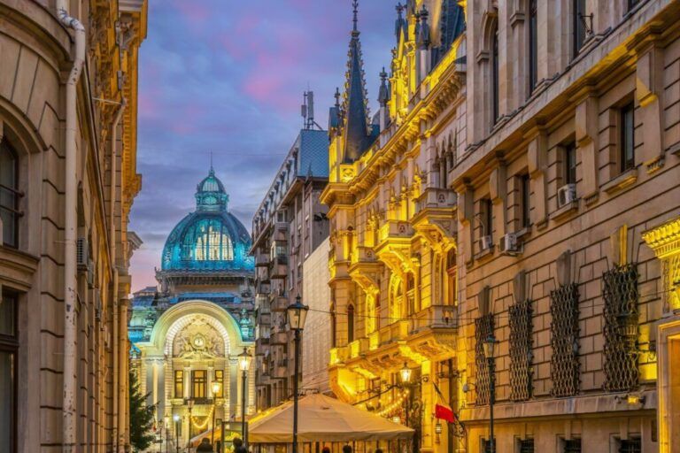 A glowing street view of the CEC Palace dome and historic architecture in Bucharest at twilight.