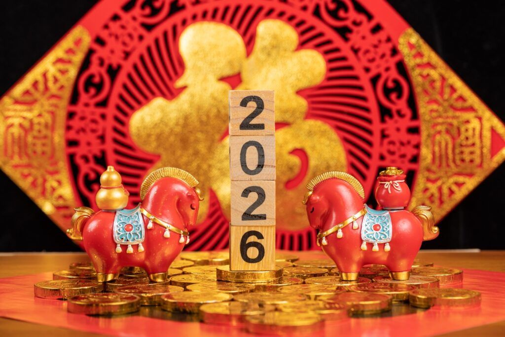 Chinese New Year 2026 celebration decorations with wooden blocks displaying the year, surrounded by red horse figurines and gold coins.
