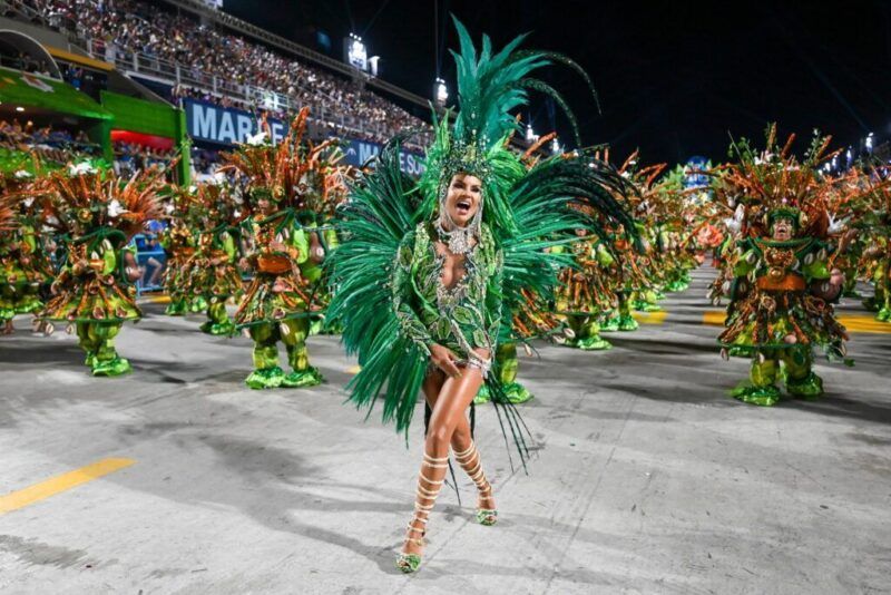 A samba dancer dressed in a bright green costume adorned with feathers parades during the carnival of Rio de Janeiro.