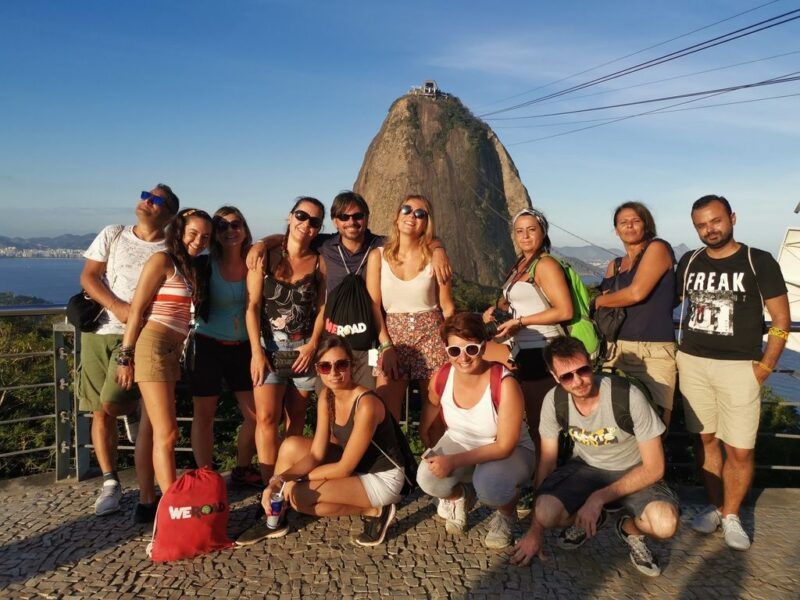 A group of WeRoads travelers posing together on a panoramic terrace with Sugarloaf Mountain in the background in Rio de Janeiro.