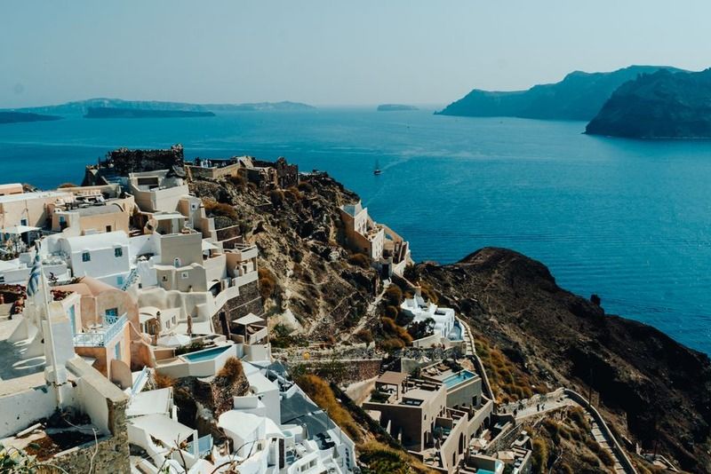 Panoramic view of Oia's white Cycladic buildings perched on the cliffs of Santorini overlooking the deep blue Aegean caldera
