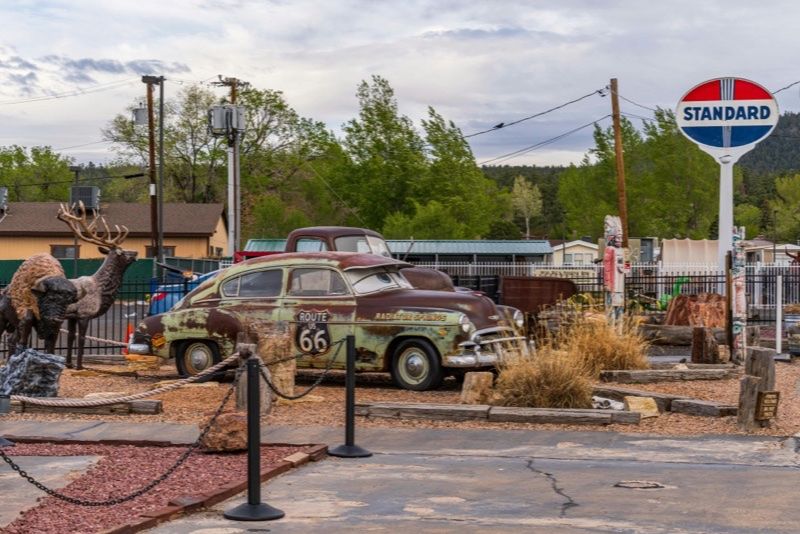 Vintage Route 66 style car beside an old roadside sign