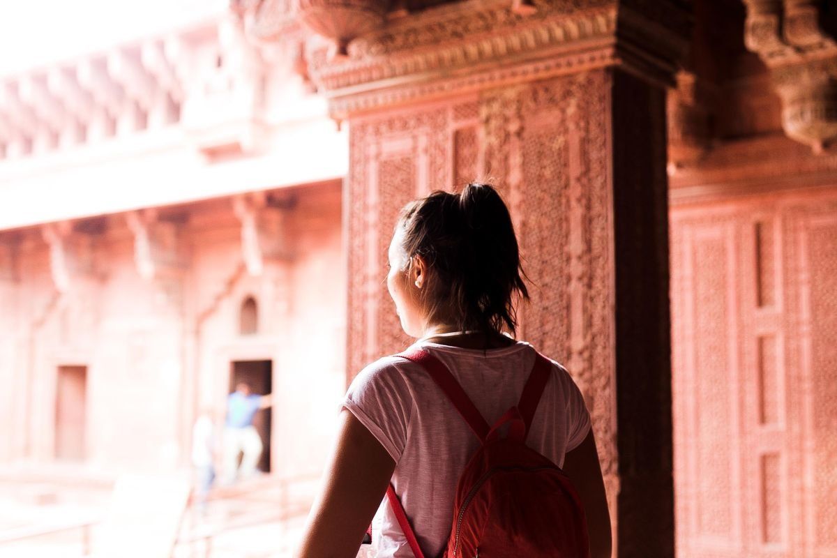 Young female traveler with backpack exploring a historic site.