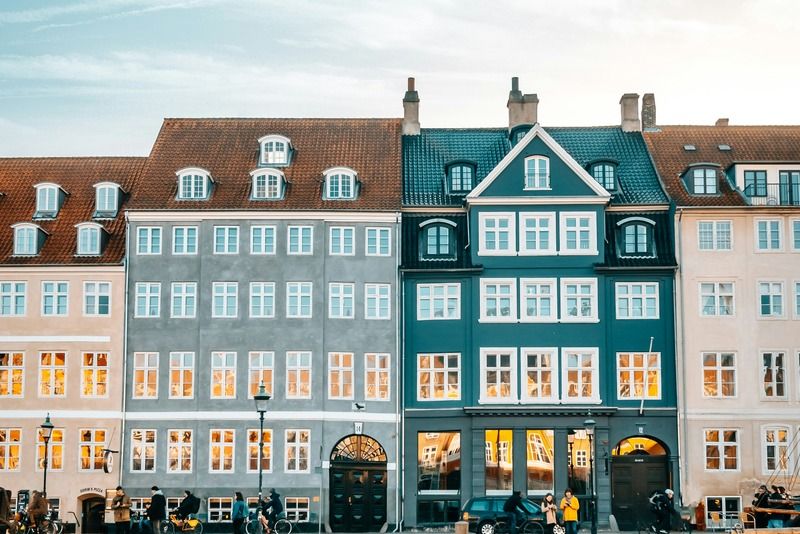 Colorful 18th-century townhouses along the Nyhavn canal waterfront in Copenhagen, Denmark, illuminated at dusk and reflected in the water