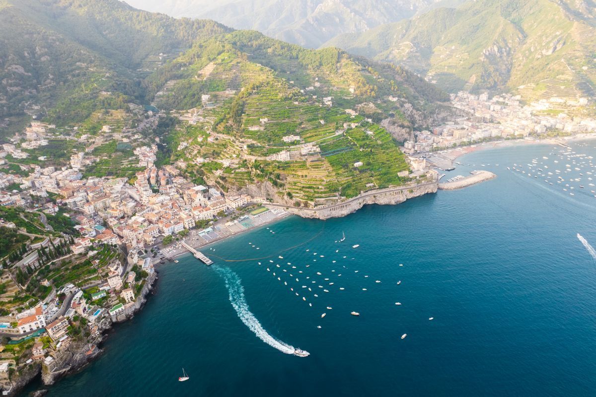 Aerial view of Amalfi Coast bays, terraced hillsides, and boats on blue water