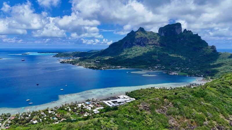 Aerial view of lush green mountains, a turquoise lagoon, and the coastline of Bora Bora